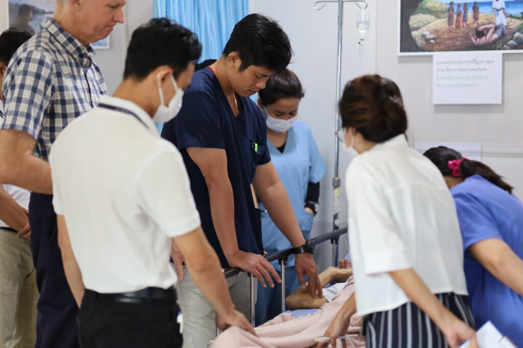 Doctors, nurses and spiritual staff praying over a patient